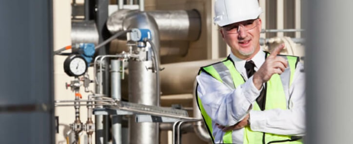 A process engineer standing outside in front of a piping installation.