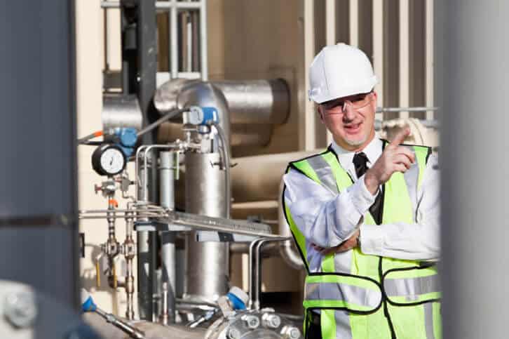 A process engineer standing outside in front of a piping installation.