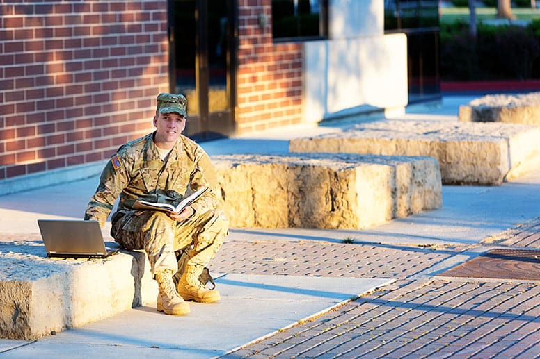 man-in-military-uniform-sitting-outside-using-laptop-to-demonstrate-how-online-learning-works