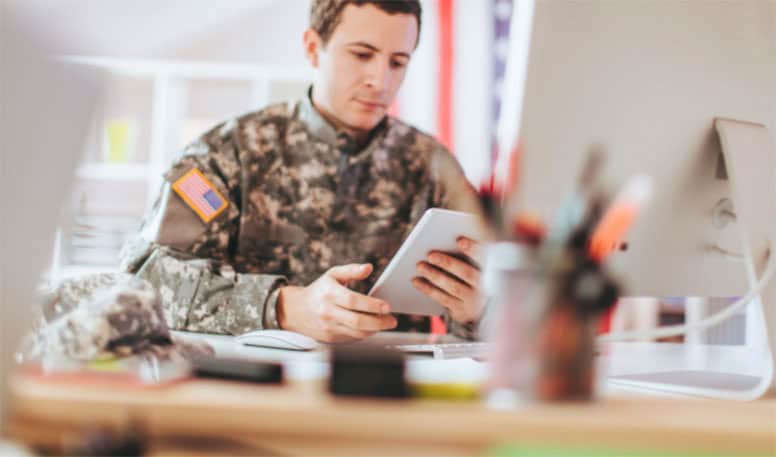 man-in-military-uniform-sitting-at-desk-using-tablet-to-demonstrate-how-the-course-works