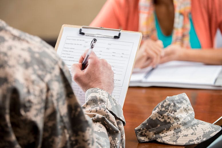 person-in-military-uniform-sitting-at-desk-with-clipboard-as-if-applying-for-scholarship