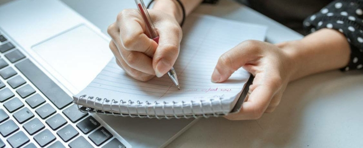 person writing clues from job advert on notepad