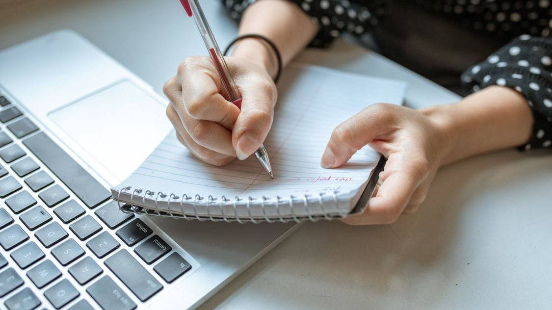 person writing clues from job advert on notepad